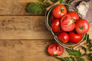 Photo of Fresh ripe tomatoes with leaves on wooden table, flat lay. Space for text