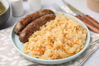 Photo of Plate with sauerkraut and sausages on table, closeup
