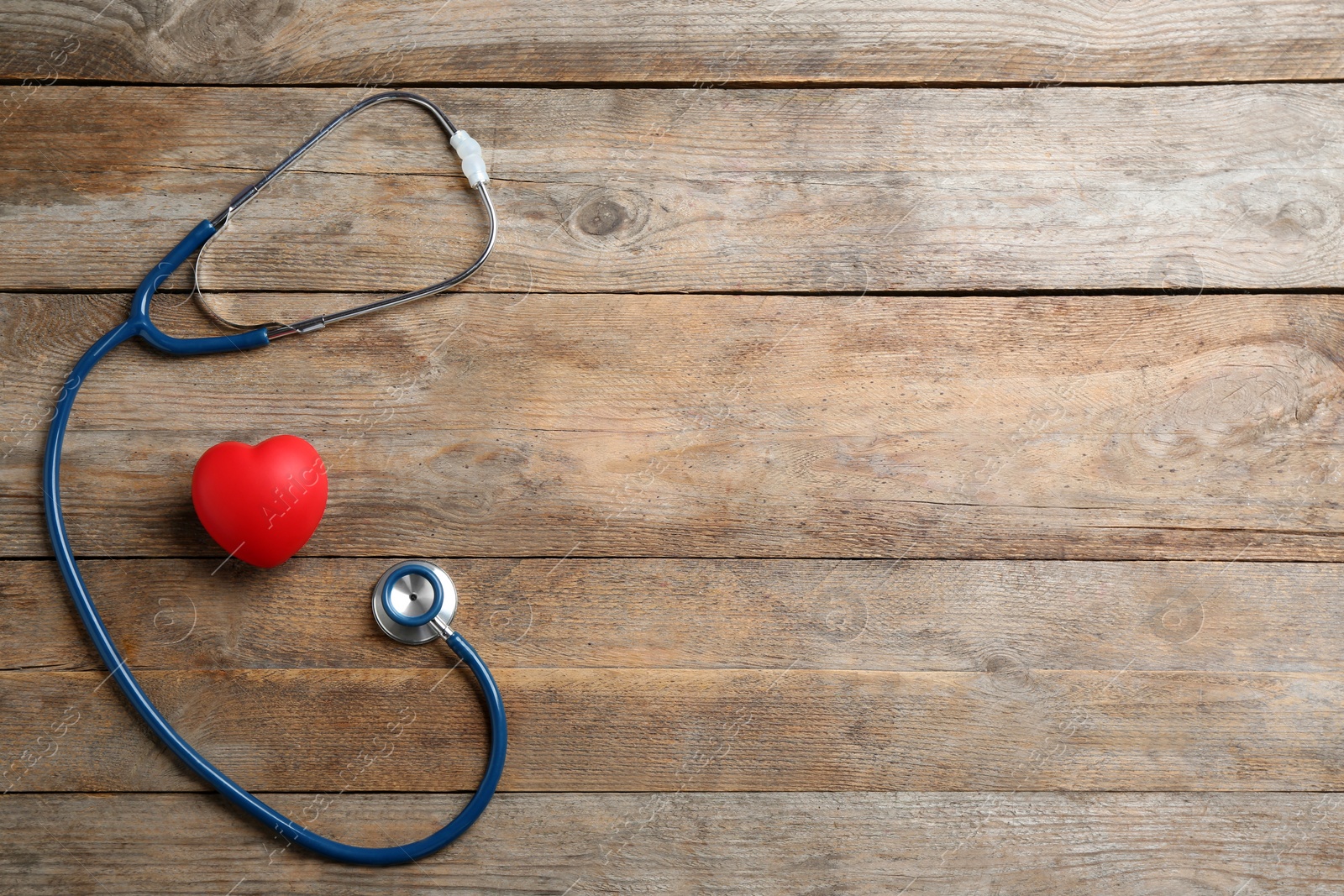 Photo of Stethoscope and red heart on wooden background, flat lay with space for text. Health insurance concept