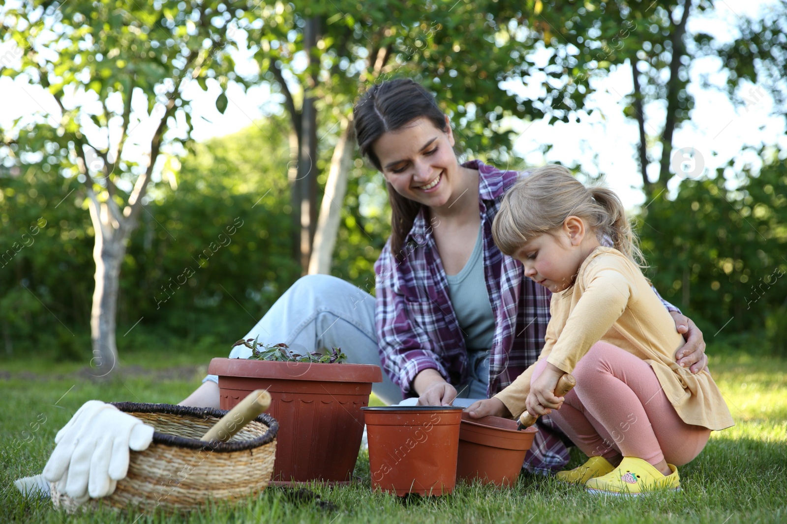 Photo of Mother and her daughter planting tree together in garden