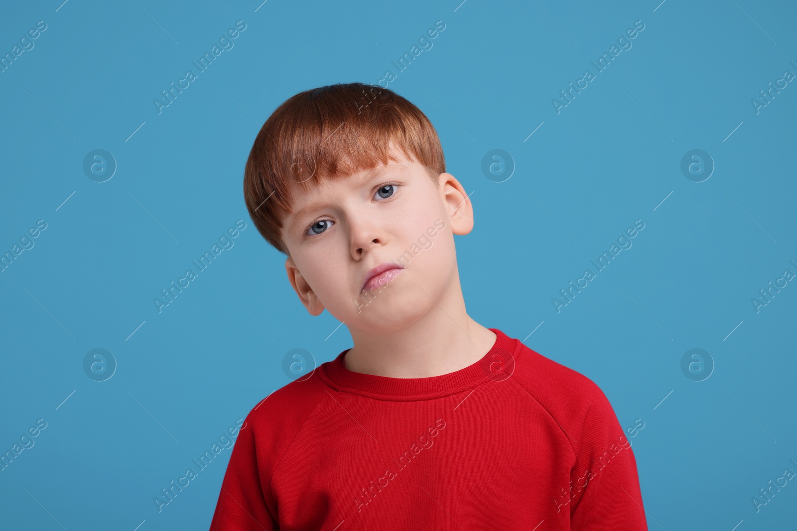 Photo of Portrait of sad little boy on light blue background