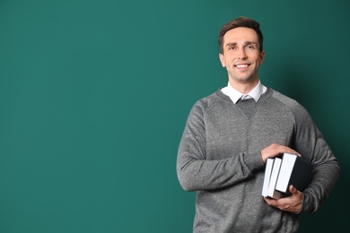 Portrait of male teacher with books on color background. Space for text