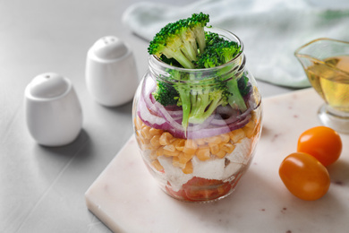 Photo of Healthy salad in glass jar on light grey table