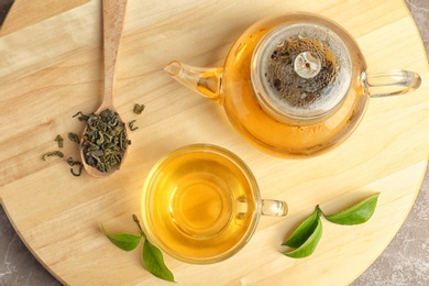 Photo of Cup of hot aromatic tea and teapot on table, top view