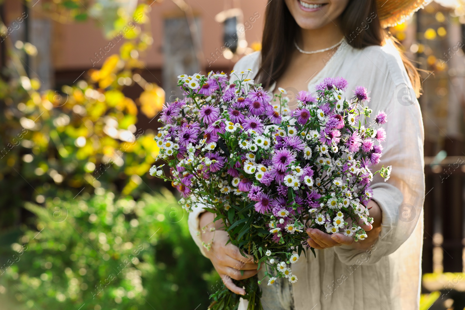 Photo of Woman holding bouquet of beautiful wild flowers outdoors, closeup. Space for text