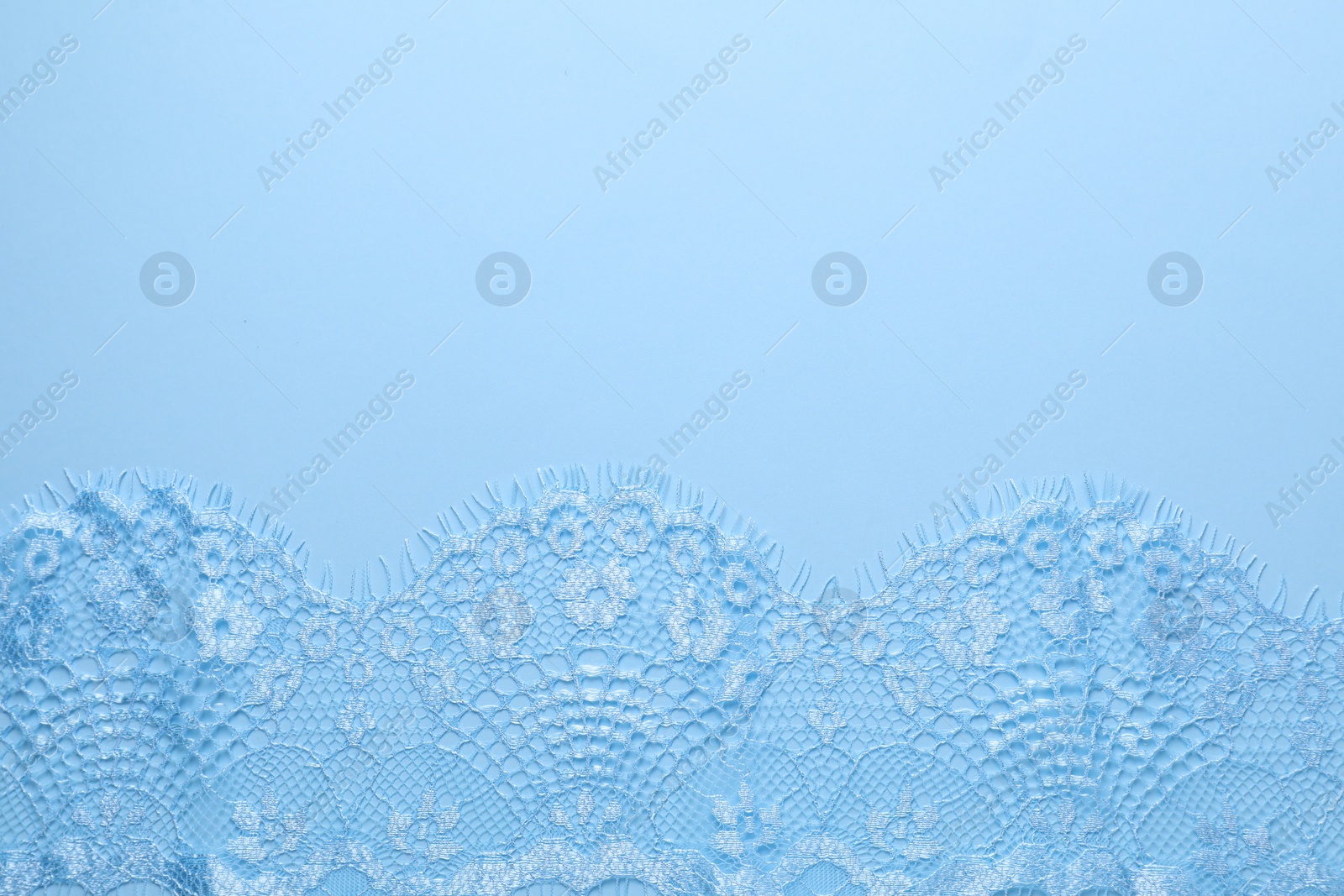 Photo of Beautiful lace on light blue background, top view. Space for text