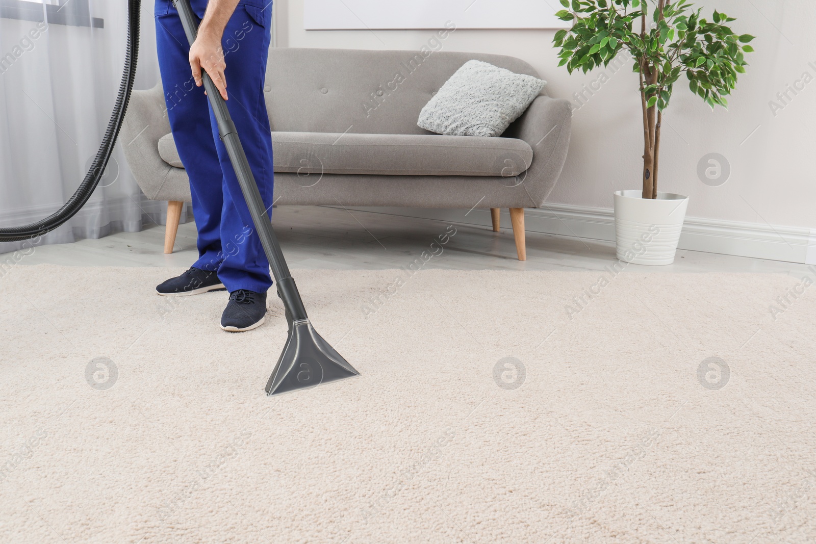 Photo of Man removing dirt from carpet with vacuum cleaner indoors, closeup. Space for text