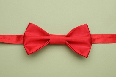 Photo of Stylish red bow tie on pale green background, top view