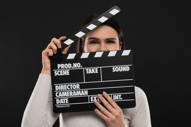 Photo of Actress with clapperboard on black background. Film industry