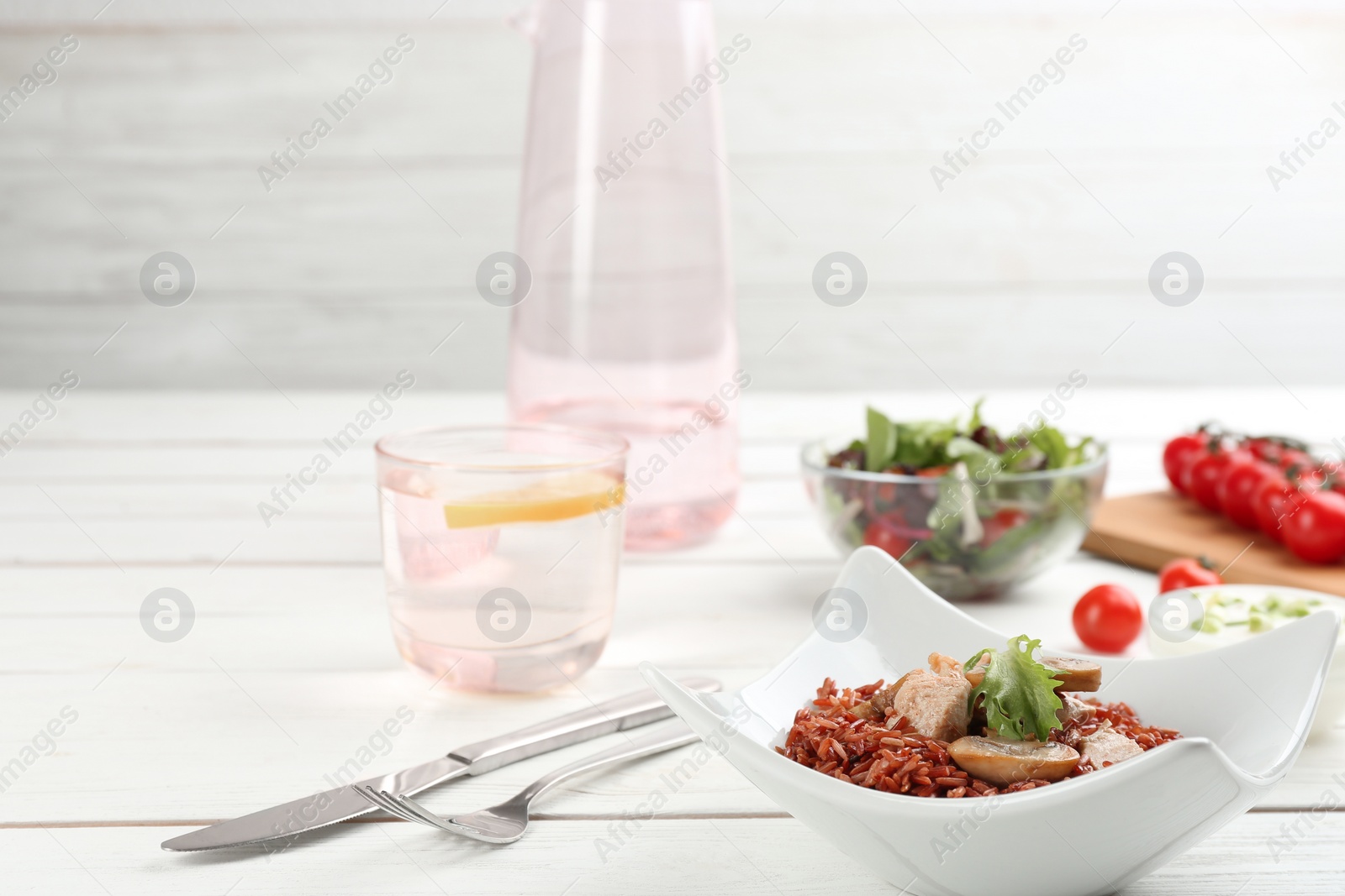 Photo of Tasty brown rice with meat and vegetables on white wooden table