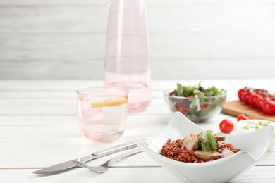 Photo of Tasty brown rice with meat and vegetables on white wooden table