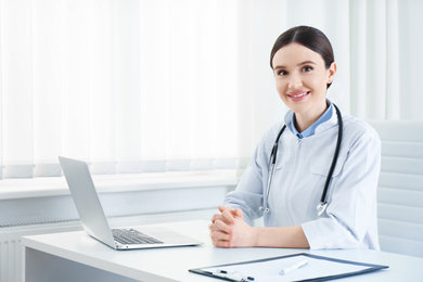 Portrait of young female doctor in white coat at workplace