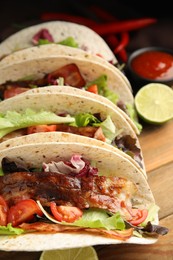 Photo of Delicious tacos with fried bacon on wooden table, closeup