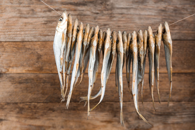 Dried fish hanging on rope against wooden background