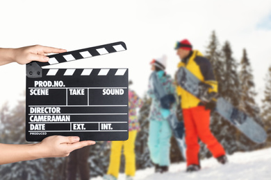 Image of Assistant holding clapperboard and people on snowy slope, closeup. Cinema production 