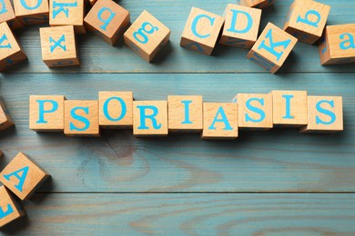 Photo of Word Psoriasis made of cubes with letters on wooden table, flat lay