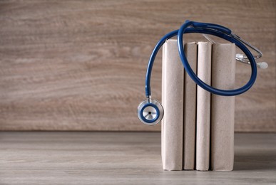 Photo of Student textbooks and stethoscope on wooden table, space for text. Medical education