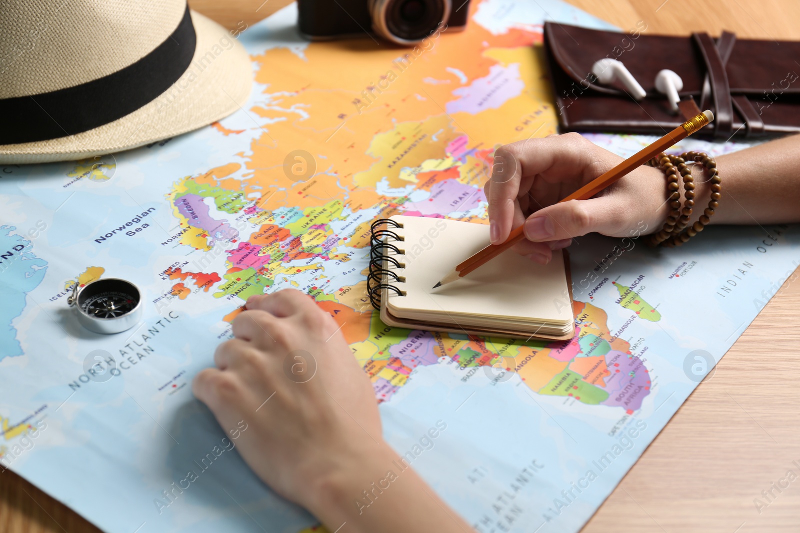 Photo of Woman with notebook and world map planning trip at wooden table, closeup