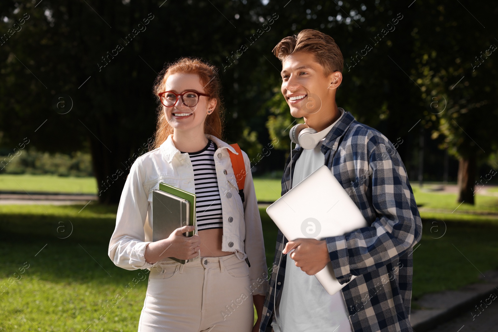 Photo of Happy young students spending time together in park