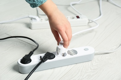 Photo of Woman inserting power plug into extension cord on floor, closeup. Electrician's professional equipment