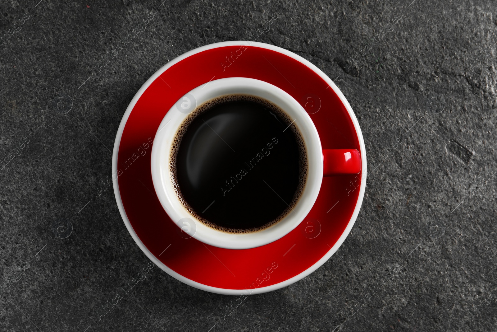 Photo of Cup with aromatic coffee on grey textured table, top view