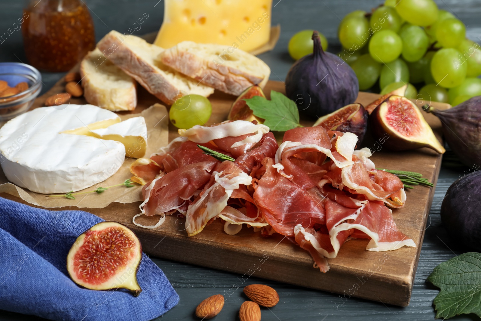 Photo of Board with delicious figs, proscuitto, cheese and grapes, closeup