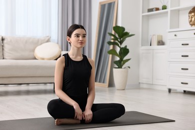 Photo of Beautiful girl meditating on yoga mat at home