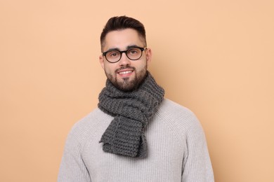 Photo of Smiling man in knitted scarf on beige background