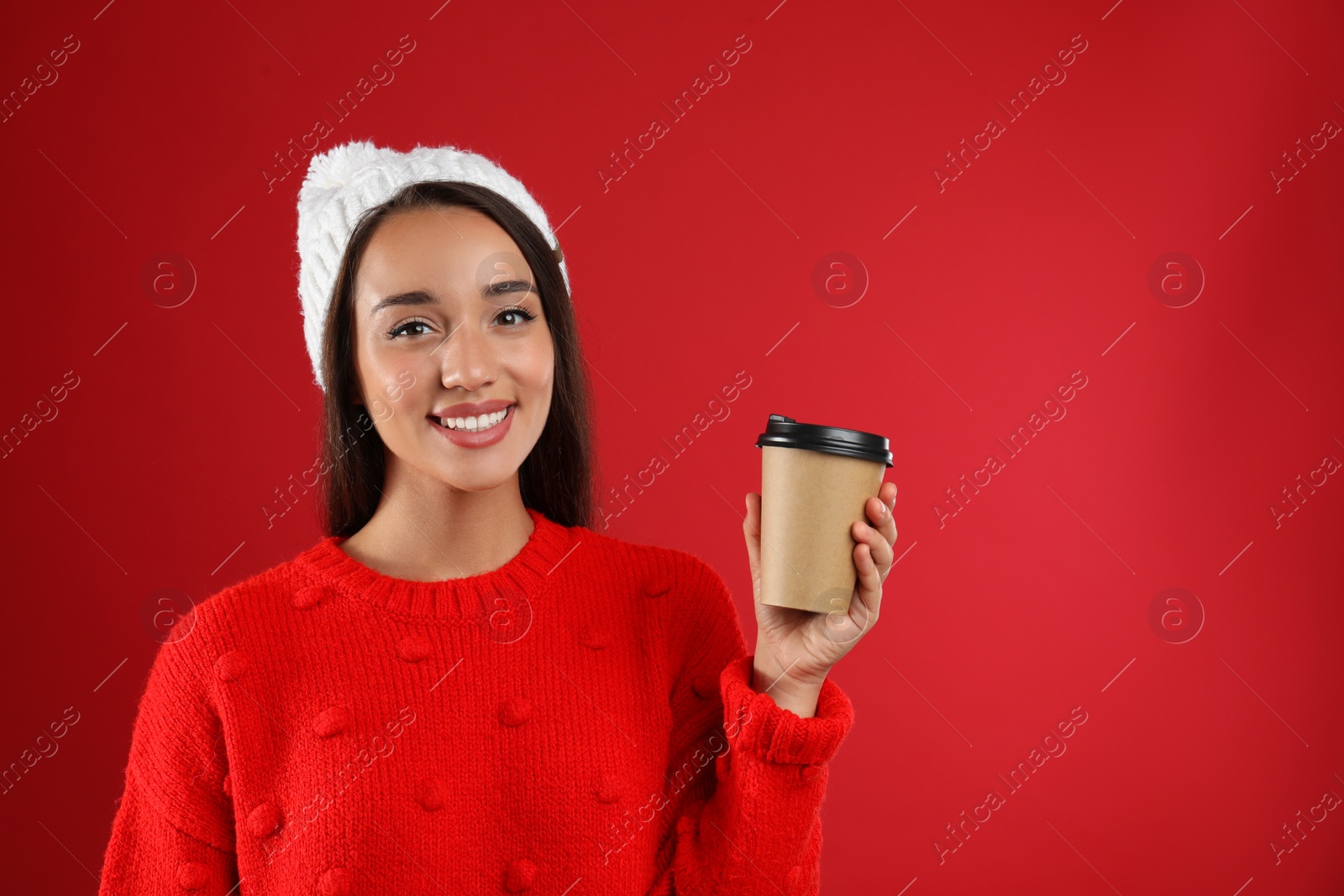 Photo of Happy beautiful woman with paper cup of mulled wine on red background. Space for text