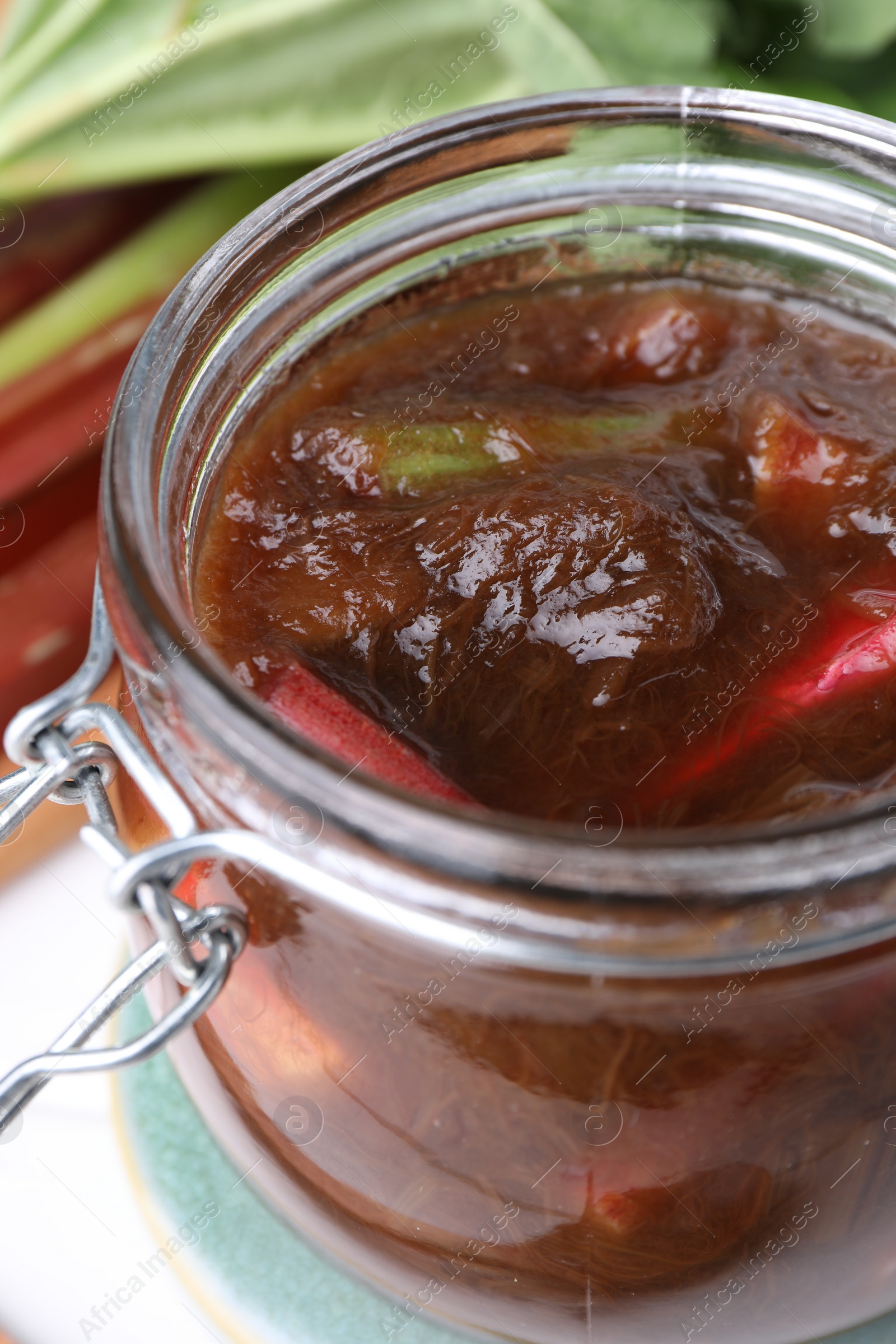 Photo of Jar of tasty rhubarb jam on white table, closeup