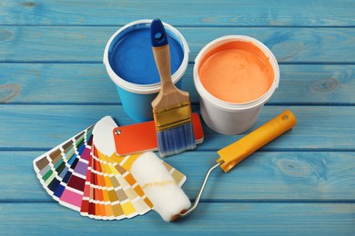 Photo of Buckets of paints, palette and decorator's tools on blue wooden background, above view