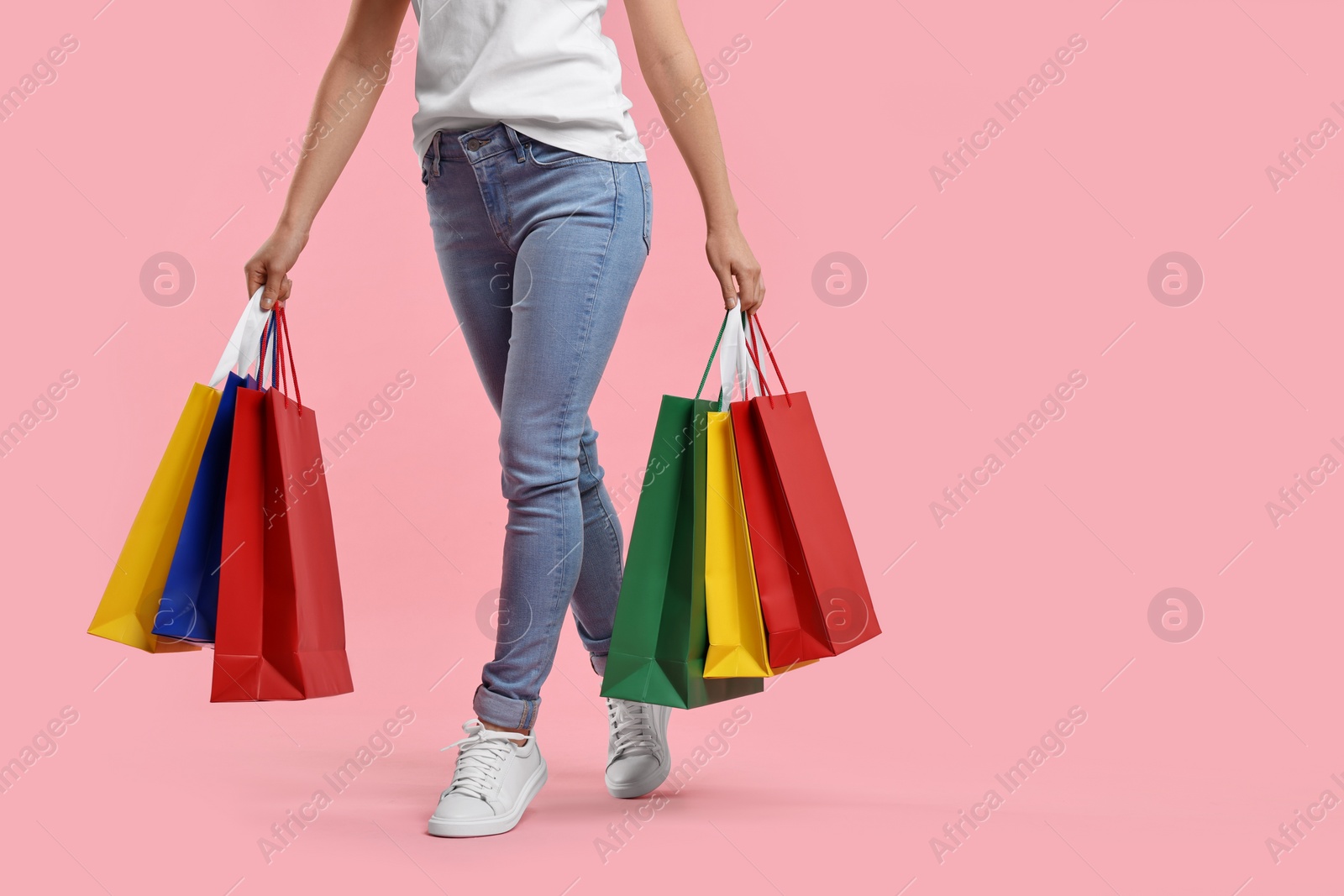 Photo of Woman with shopping bags on pink background, closeup. Space for text