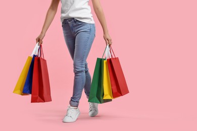 Woman with shopping bags on pink background, closeup. Space for text