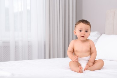 Cute baby in dry soft diaper on white bed at home