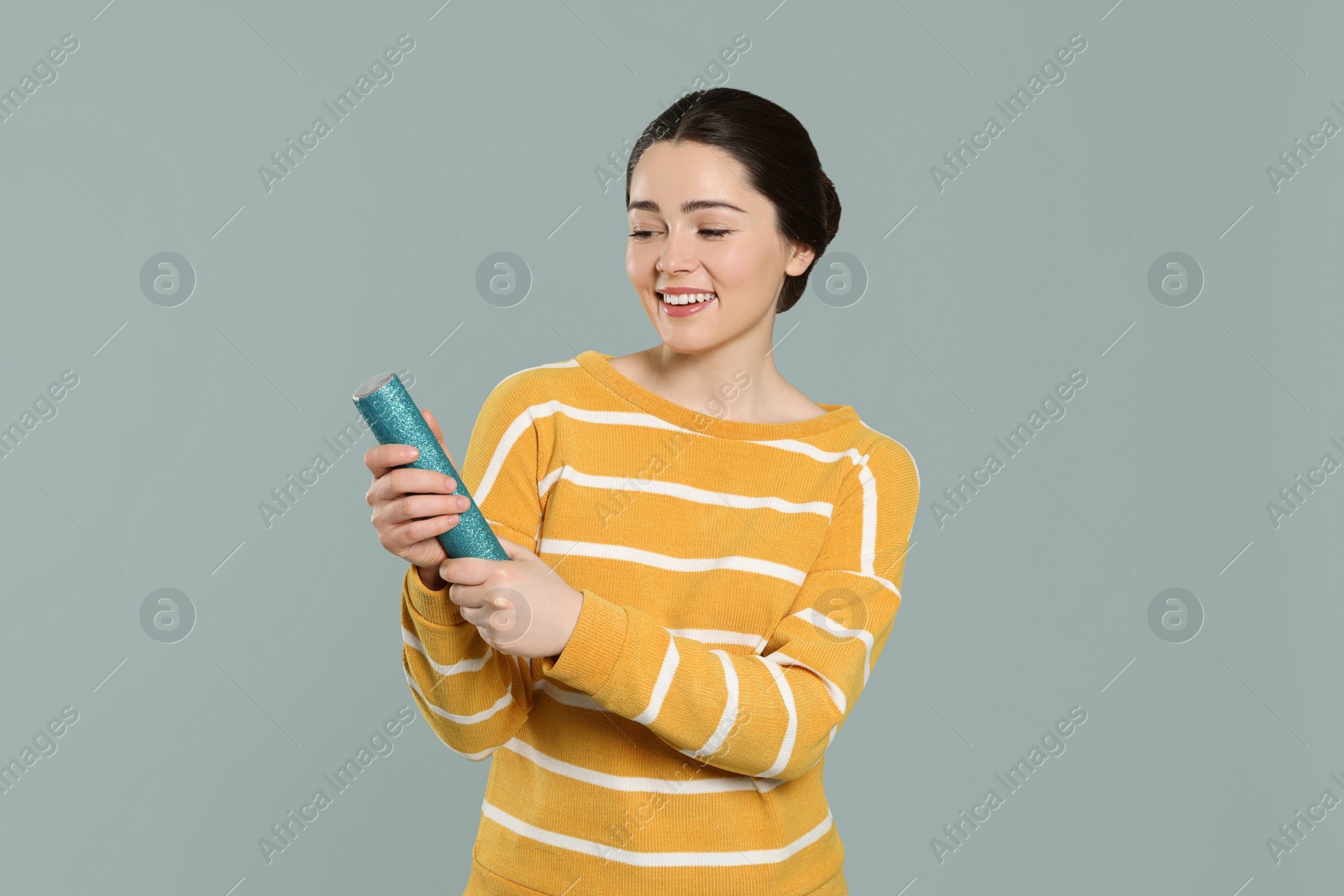 Photo of Young woman blowing up party popper on light grey background