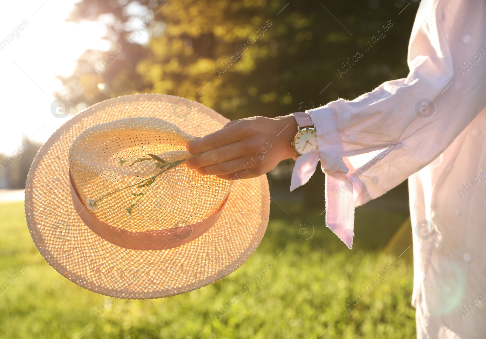 Photo of Young woman with straw hat and flowers outdoors on sunny day, closeup