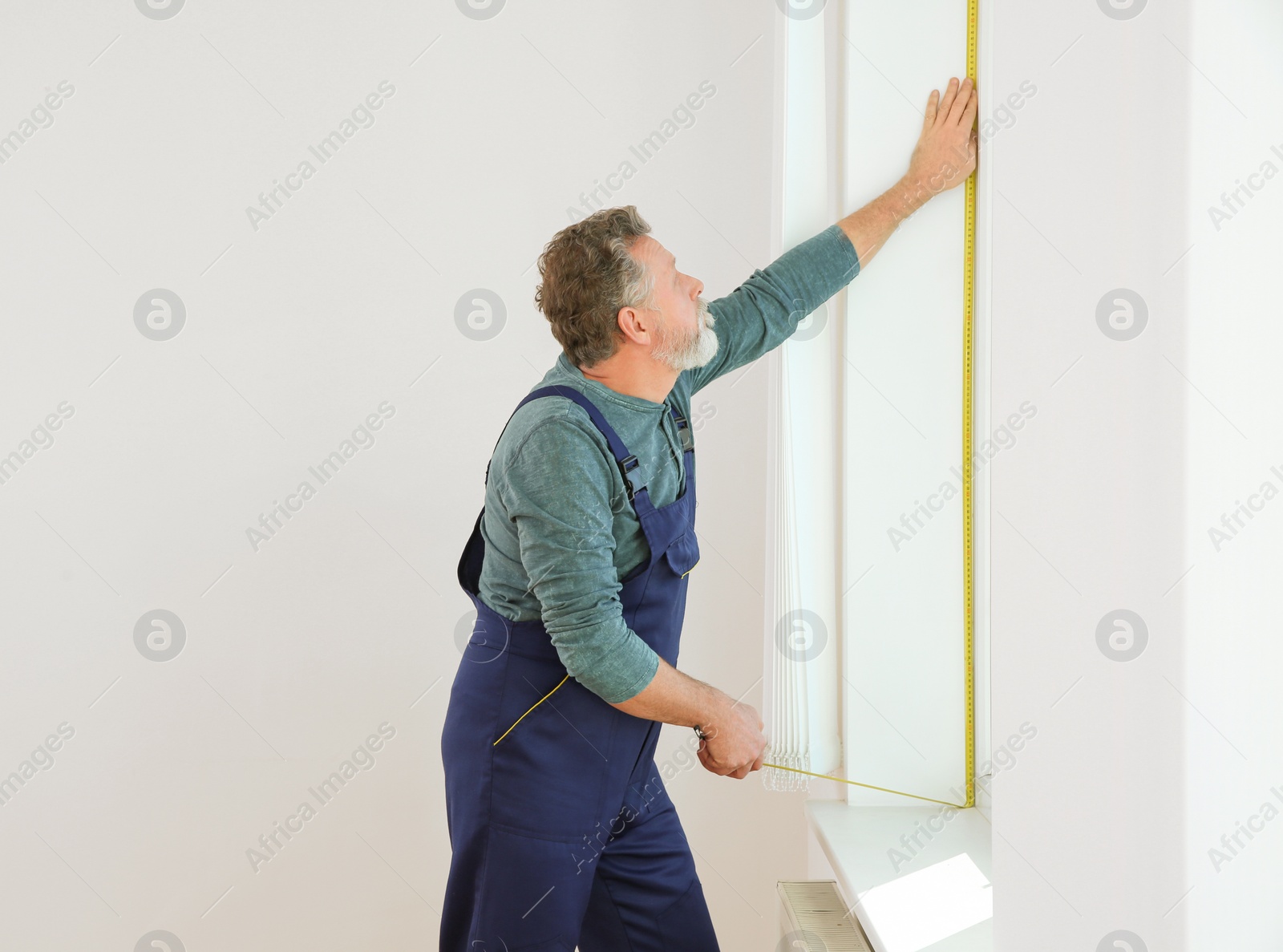 Photo of Service man measuring window for installation indoors. Space for text