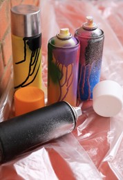 Photo of Used cans of spray paints on table near brick wall. Graffiti supplies