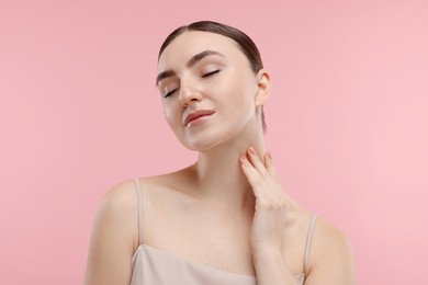 Photo of Beautiful woman touching her neck on pink background