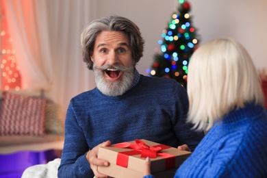 Happy couple opening Christmas gift at home