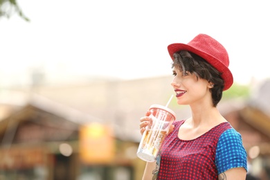 Photo of Young woman with cup of tasty lemonade outdoors