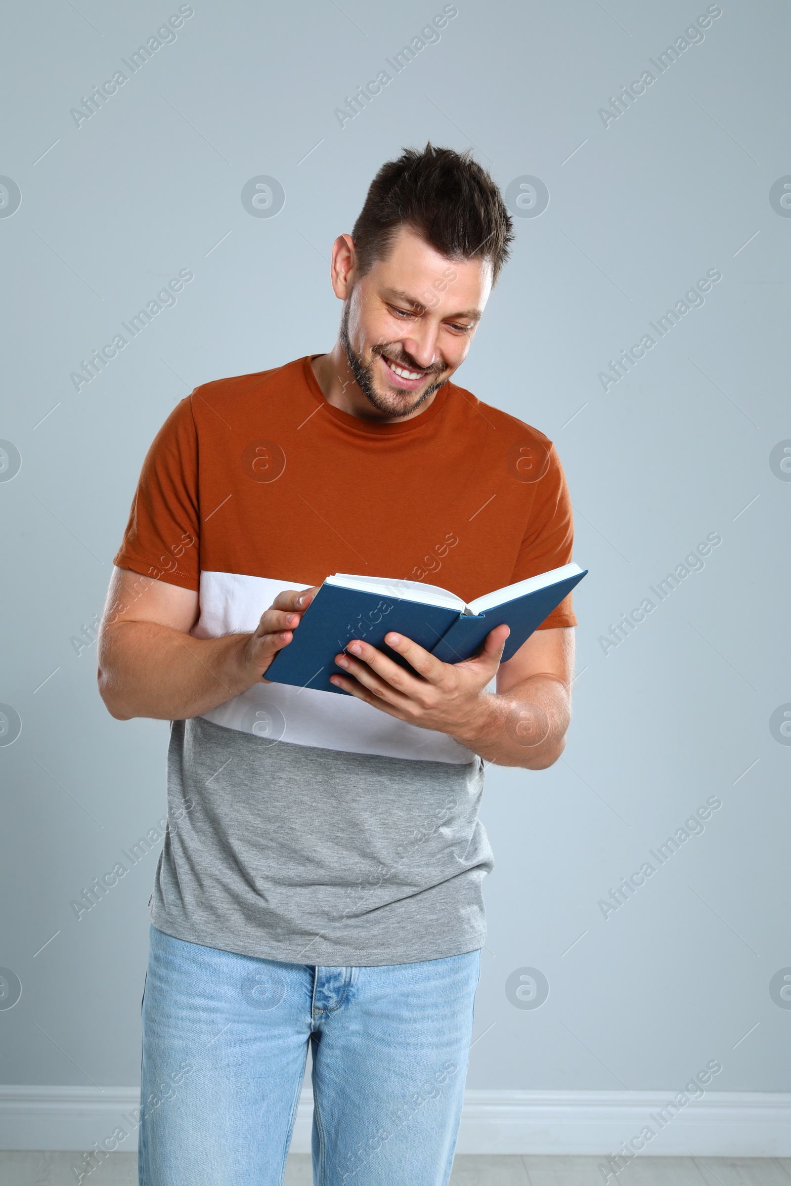 Photo of Handsome man reading book against light background