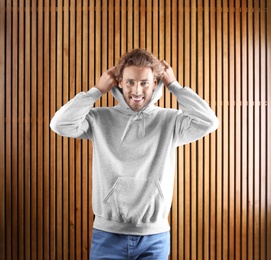 Portrait of man in hoodie sweater on wooden background. Space for design