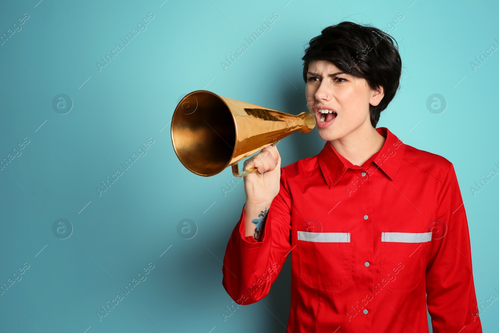 Photo of Young female doctor shouting into megaphone on color background