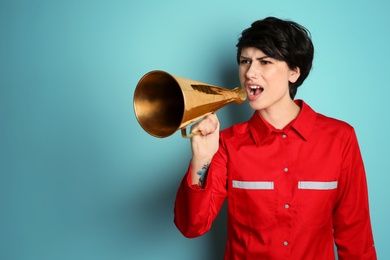 Young female doctor shouting into megaphone on color background