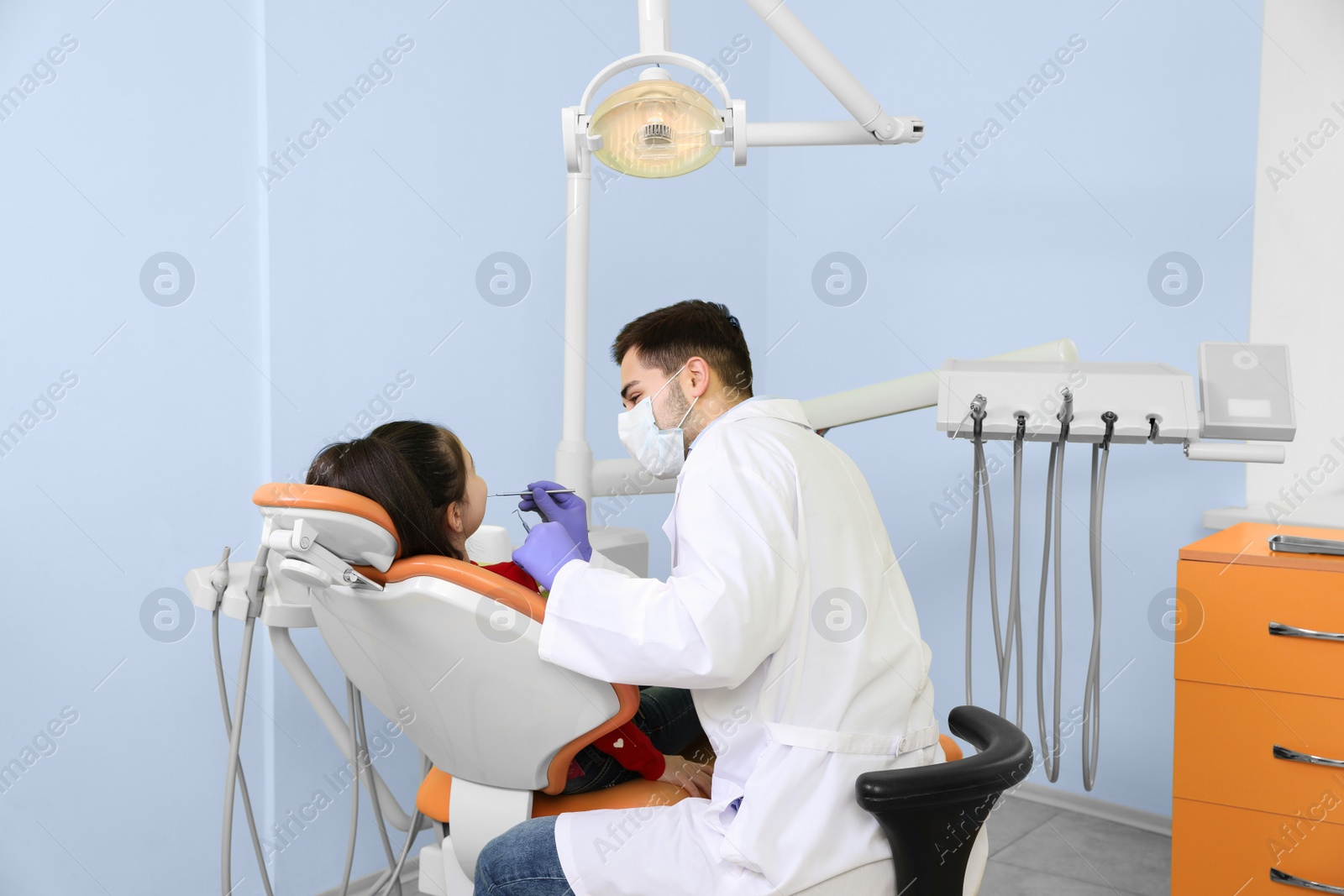 Photo of Professional dentist working with little patient in modern clinic