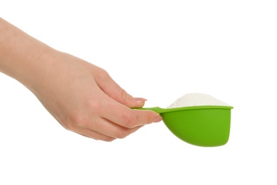 Woman holding scoop with laundry detergent on white background, closeup