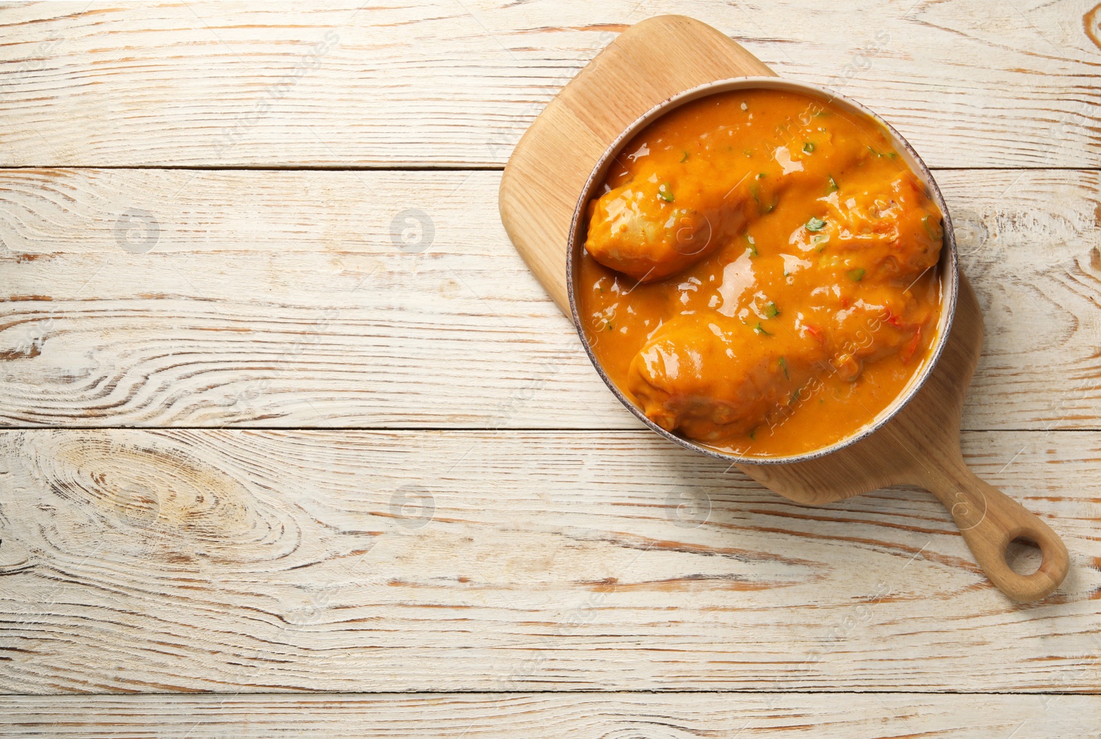 Photo of Tasty chicken curry on wooden table, top view. Space for text