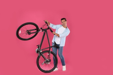 Photo of Handsome young man with modern bicycle on pink background