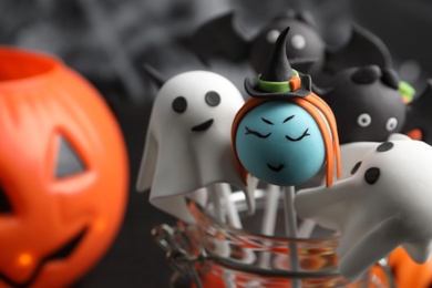 Different Halloween themed cake pops on dark background, closeup